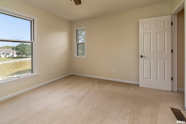 carpeted spare room featuring a healthy amount of sunlight and ceiling fan