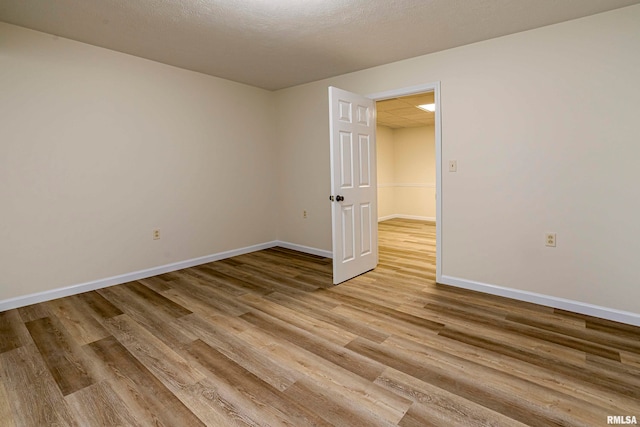 empty room featuring light wood-type flooring and a textured ceiling