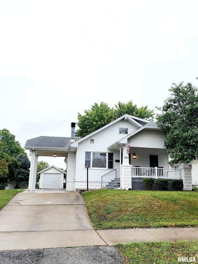 view of front of house featuring covered porch, a garage, an outbuilding, and a front yard