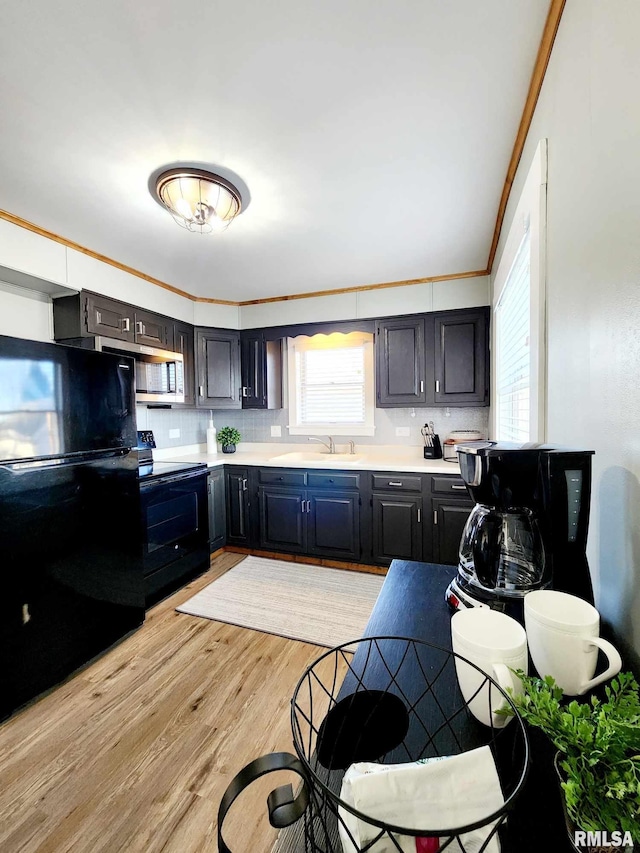 kitchen with backsplash, black appliances, sink, ornamental molding, and light hardwood / wood-style floors