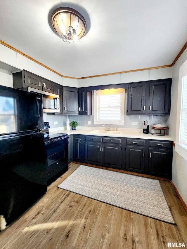 kitchen featuring light wood-type flooring, tasteful backsplash, crown molding, sink, and black appliances