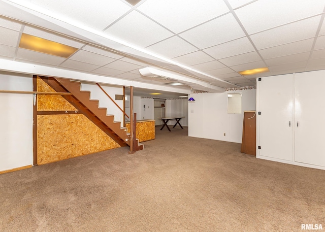 basement with a paneled ceiling and carpet