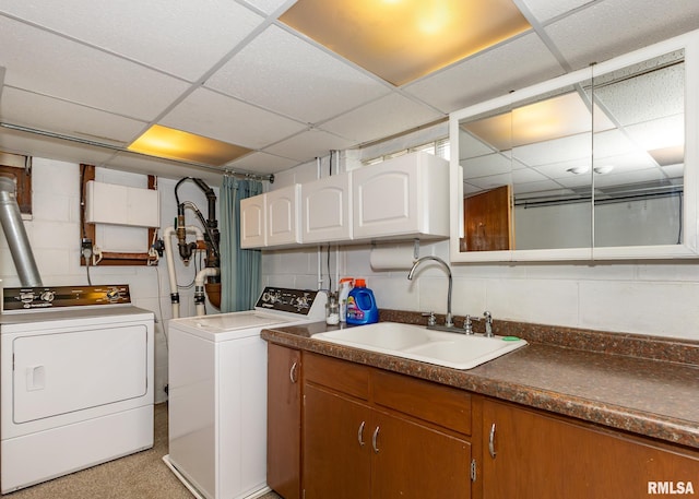 clothes washing area with cabinets, sink, and washer and dryer