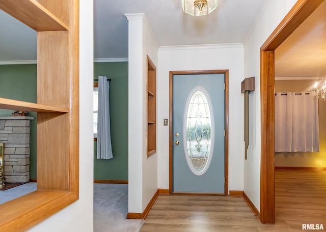 foyer entrance with ornamental molding, a fireplace, and light wood-type flooring