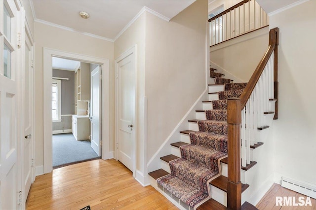 stairway featuring a baseboard radiator, hardwood / wood-style floors, and crown molding