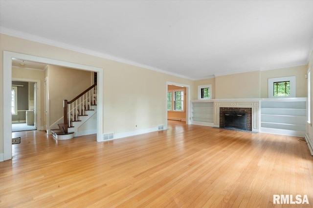 unfurnished living room featuring a brick fireplace, ornamental molding, light hardwood / wood-style floors, and a baseboard heating unit