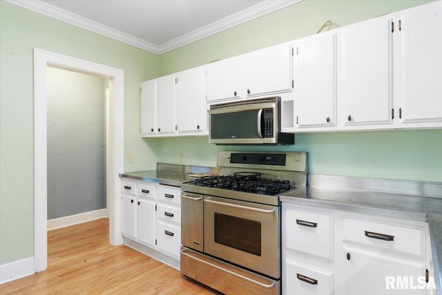 kitchen with white cabinets, appliances with stainless steel finishes, light wood-type flooring, and crown molding