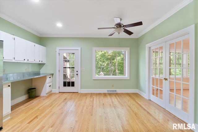 interior space featuring light wood-type flooring, built in desk, crown molding, ceiling fan, and french doors