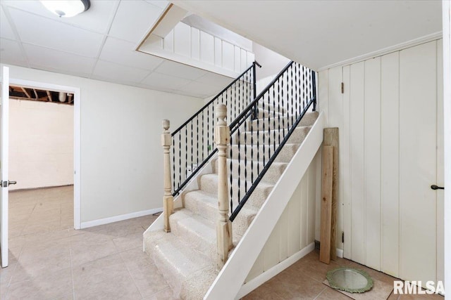 stairway featuring a drop ceiling and tile patterned floors