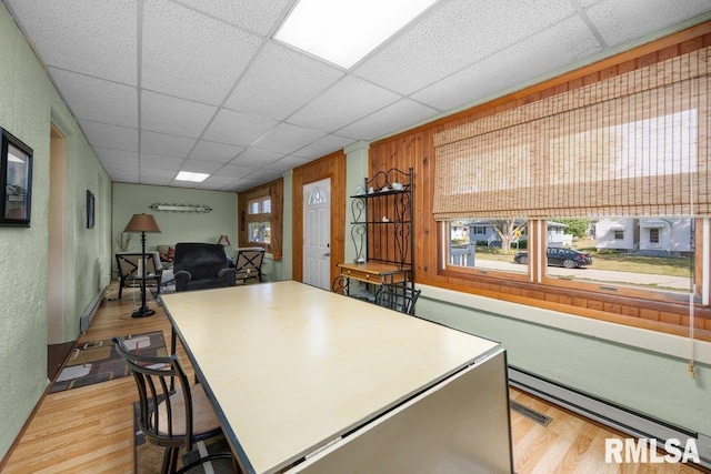 kitchen with light wood-type flooring, a drop ceiling, and wood walls