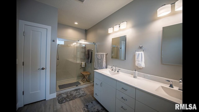 bathroom with vanity, a shower with shower door, hardwood / wood-style floors, and a textured ceiling