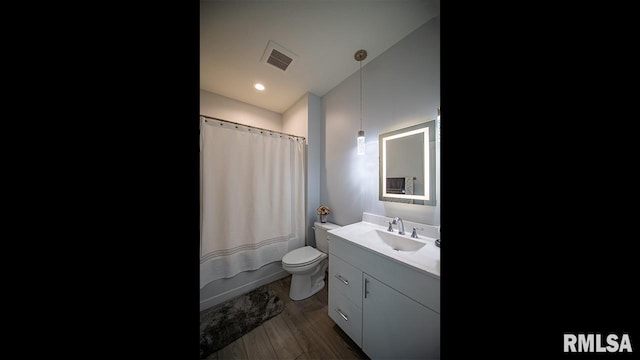 full bathroom featuring hardwood / wood-style floors, vanity, shower / bath combo with shower curtain, and toilet