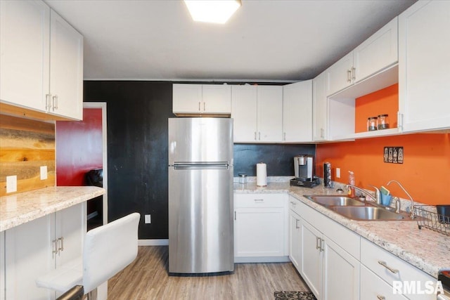 kitchen featuring stainless steel refrigerator, white cabinets, and sink