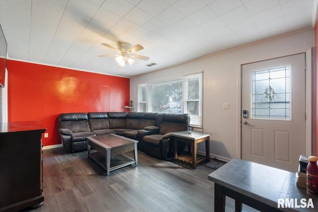 living room with crown molding, ceiling fan, and dark wood-type flooring