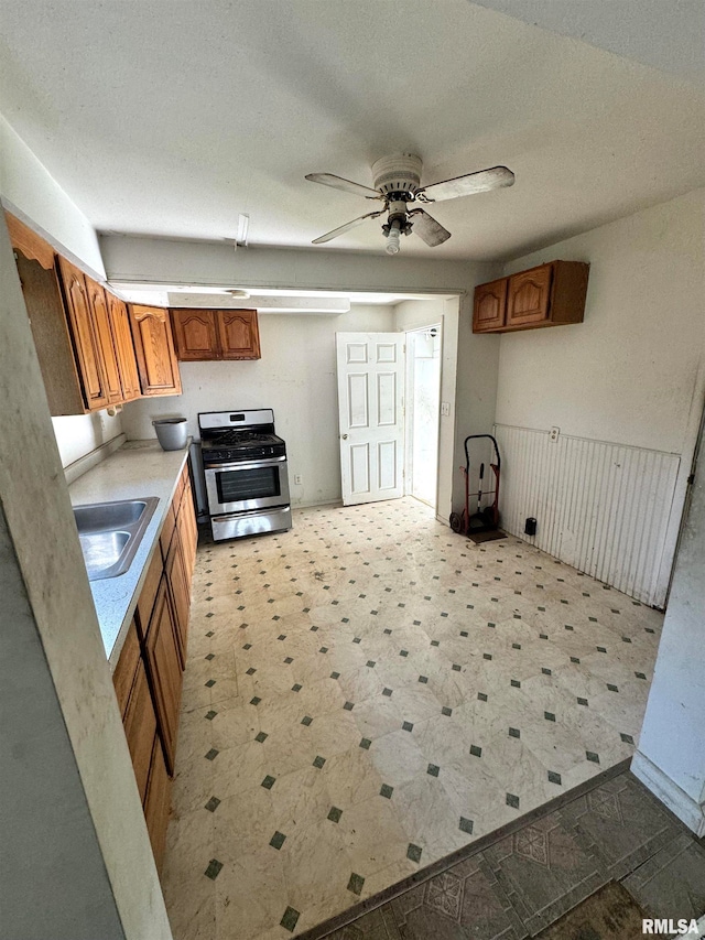 kitchen with ceiling fan, stainless steel gas range oven, sink, and a textured ceiling