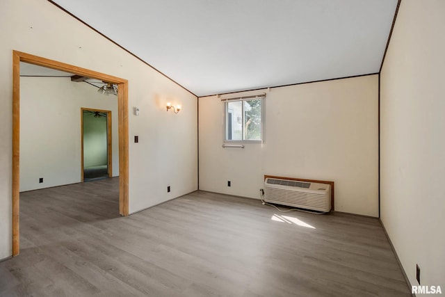 spare room featuring lofted ceiling, light hardwood / wood-style floors, and a wall mounted AC