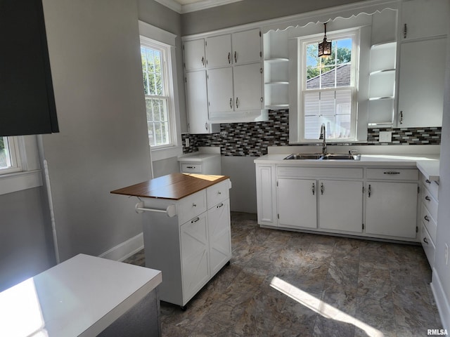 kitchen featuring white cabinets, backsplash, a kitchen island, and sink