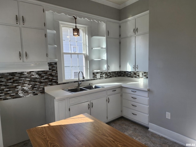 kitchen with decorative backsplash, white cabinetry, crown molding, and sink