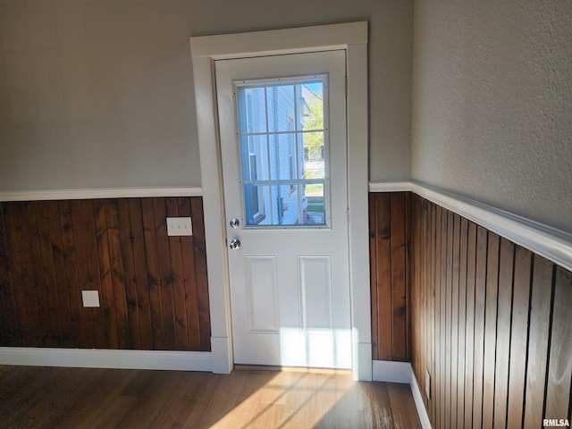 doorway featuring light hardwood / wood-style flooring and wooden walls