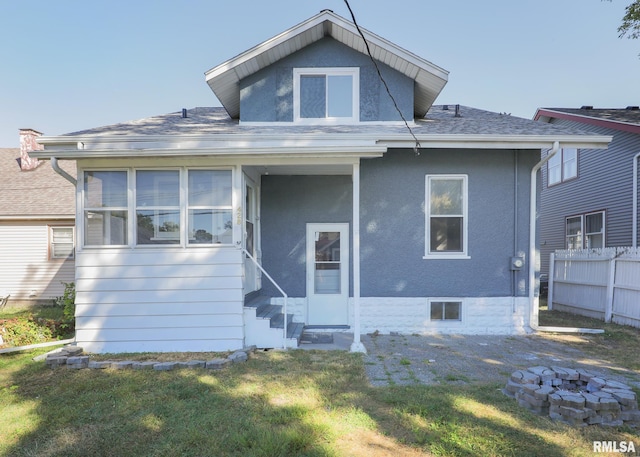 rear view of house featuring a yard and a sunroom