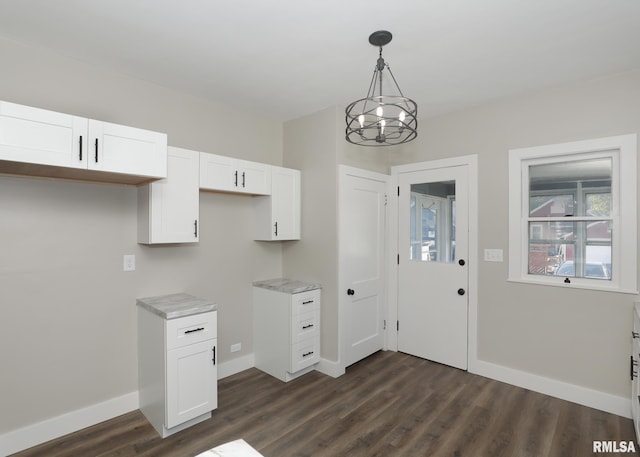 kitchen with dark hardwood / wood-style flooring, light stone counters, decorative light fixtures, an inviting chandelier, and white cabinetry