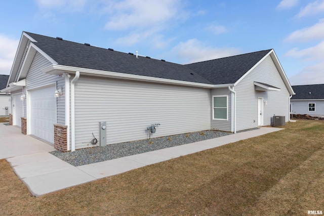 view of side of home featuring a lawn, central AC unit, and a garage