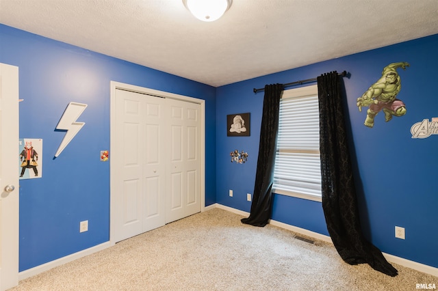 unfurnished bedroom with light colored carpet, a textured ceiling, and a closet