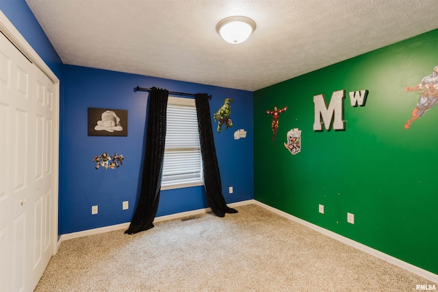 unfurnished bedroom featuring a textured ceiling, carpet floors, and a closet