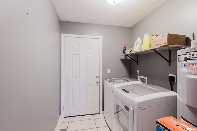 laundry room with light tile patterned floors, a textured ceiling, water heater, and washing machine and dryer