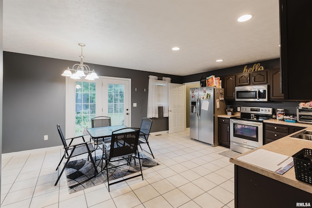 kitchen featuring hanging light fixtures, light tile patterned floors, stainless steel appliances, an inviting chandelier, and dark brown cabinets