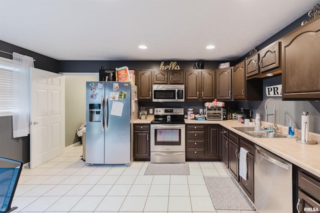 kitchen featuring dark brown cabinets, light tile patterned flooring, stainless steel appliances, and sink