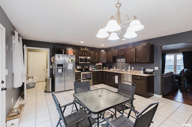 kitchen featuring a chandelier, light hardwood / wood-style flooring, stainless steel appliances, decorative light fixtures, and dark brown cabinetry