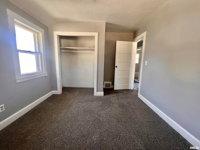 unfurnished bedroom with dark carpet and a closet