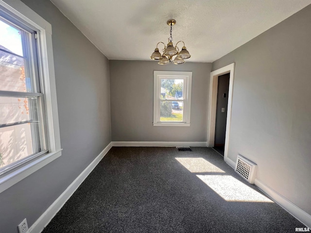 spare room with carpet floors, a notable chandelier, and a textured ceiling