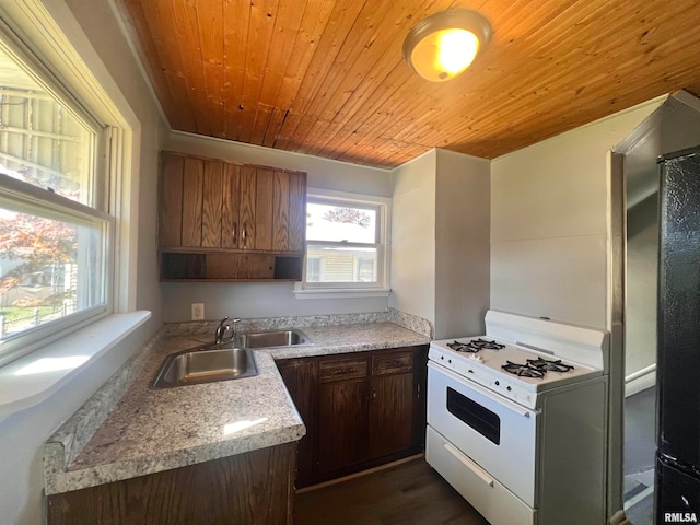 kitchen featuring wood ceiling, dark wood-type flooring, gas range gas stove, light stone countertops, and sink