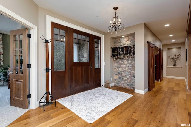 foyer entrance featuring an inviting chandelier, light hardwood / wood-style flooring, and a barn door