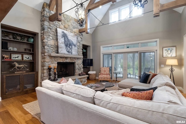 living room featuring high vaulted ceiling, beamed ceiling, a stone fireplace, french doors, and light hardwood / wood-style floors