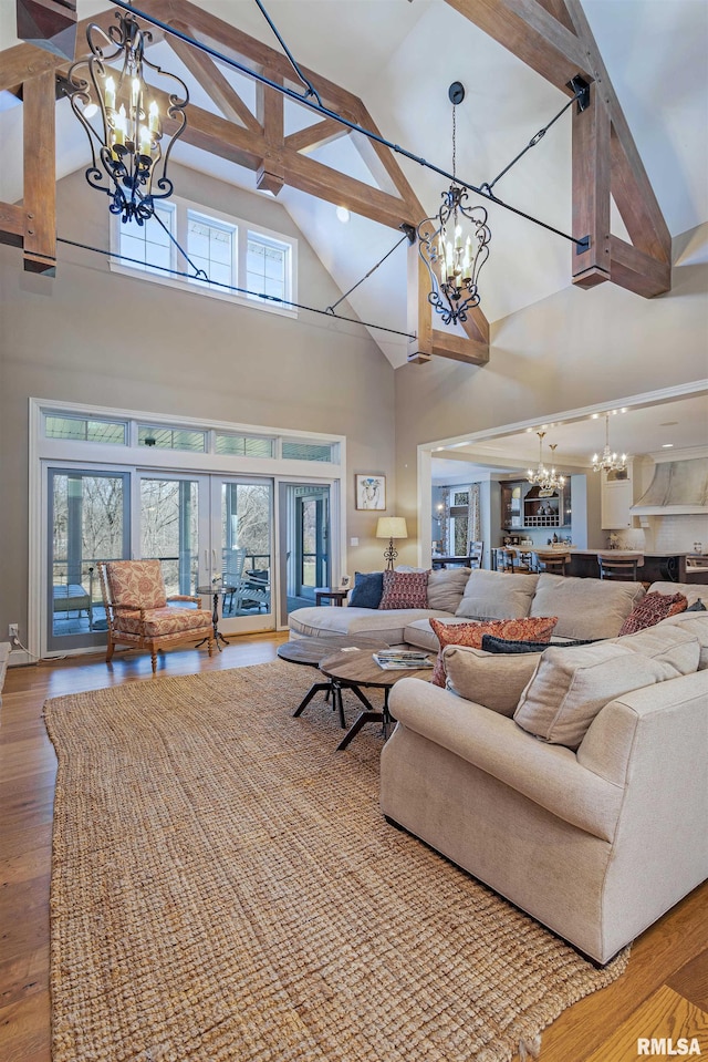 living room featuring hardwood / wood-style floors, a chandelier, beam ceiling, and high vaulted ceiling