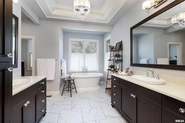 bathroom with a tub to relax in, a tray ceiling, vanity, crown molding, and an inviting chandelier