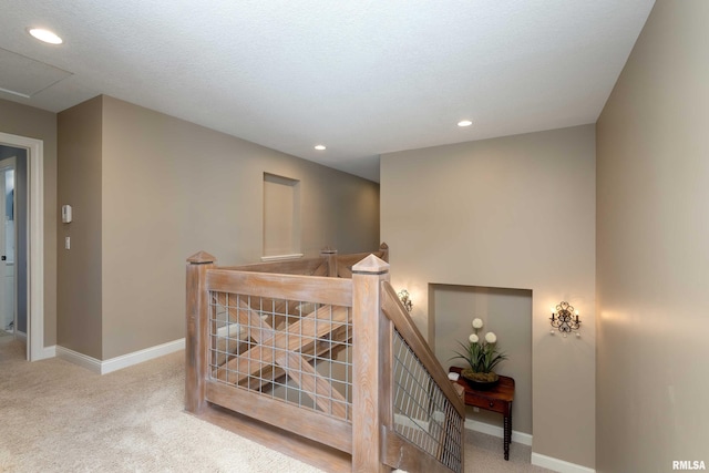 hall featuring light carpet and a textured ceiling