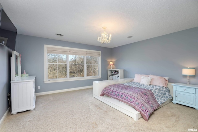 carpeted bedroom featuring a notable chandelier and a textured ceiling