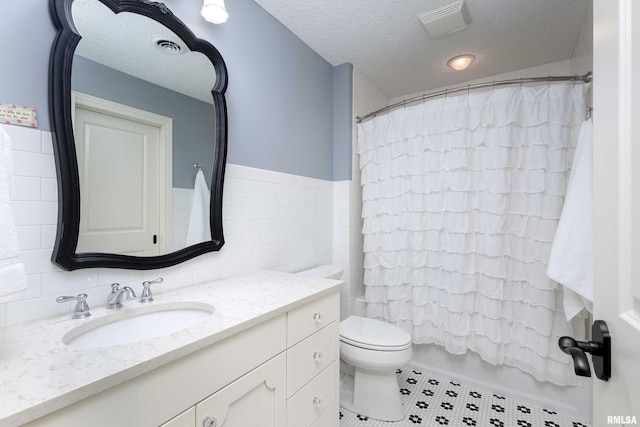 full bathroom with a textured ceiling, shower / bath combination with curtain, toilet, vanity, and tile patterned flooring