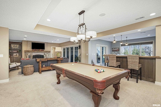 playroom with pool table, light carpet, bar, and a textured ceiling