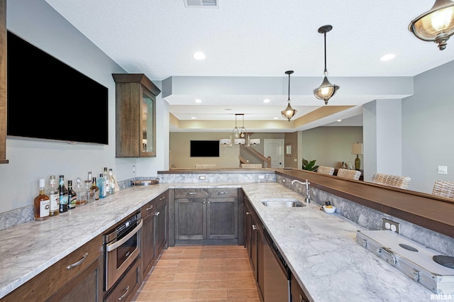 kitchen with light hardwood / wood-style flooring, light stone countertops, sink, and hanging light fixtures