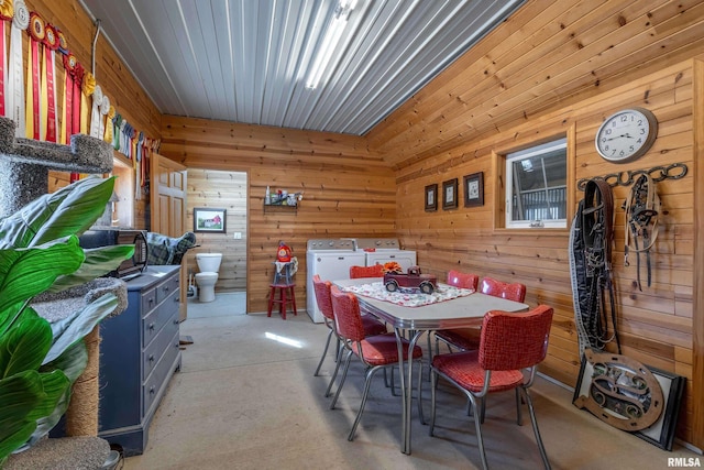 dining room featuring washing machine and dryer and wood walls