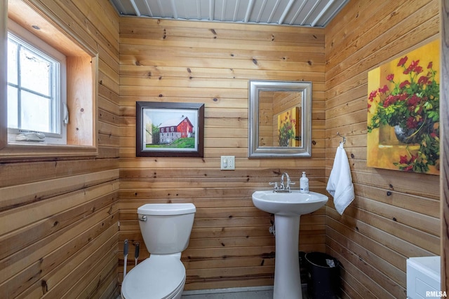 bathroom with toilet and wood walls