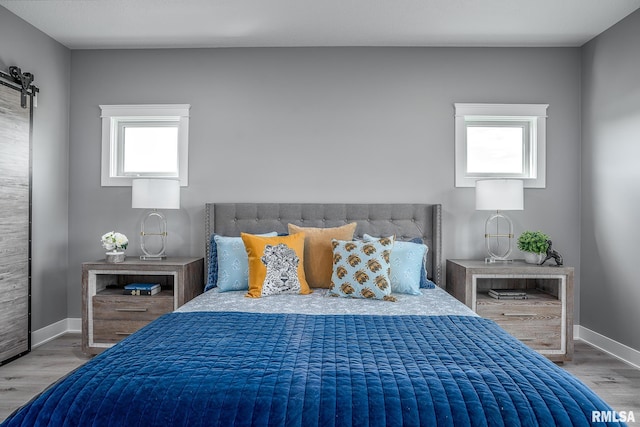 bedroom featuring multiple windows, hardwood / wood-style floors, and a barn door