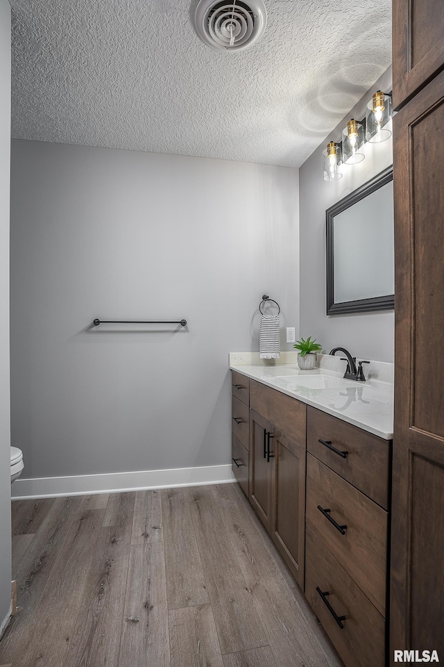 bathroom with vanity, wood-type flooring, a textured ceiling, and toilet