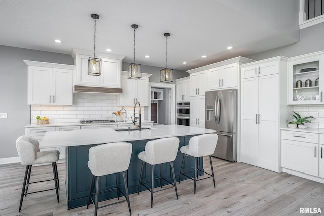 kitchen with white cabinets, appliances with stainless steel finishes, hanging light fixtures, and sink