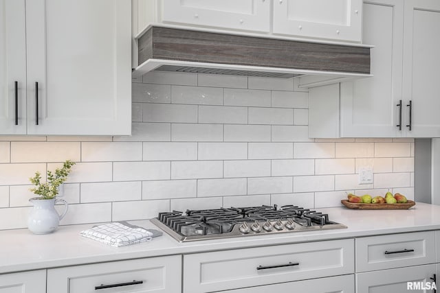 kitchen with decorative backsplash, white cabinets, and stainless steel gas stovetop